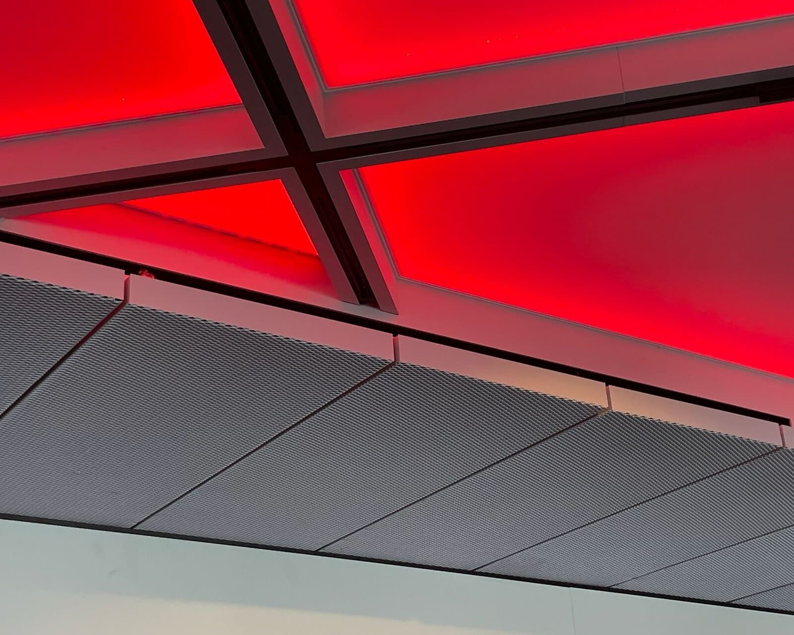 Stalen onderconstructie onder een verlicht spanplafond — een realisatie van de groep